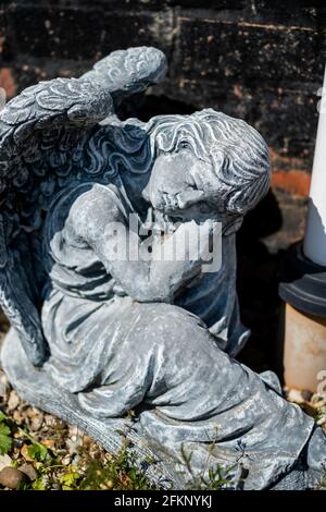 Fuoco vicino e selettivo di una statuetta dell'angelo in a. cortile posteriore privato con profondità di campo intenzionale poco profonda e. bokeh Foto Stock