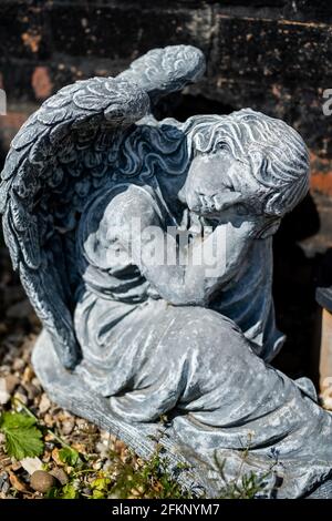 Fuoco vicino e selettivo di una statuetta dell'angelo in a. cortile posteriore privato con profondità di campo intenzionale poco profonda e. bokeh Foto Stock