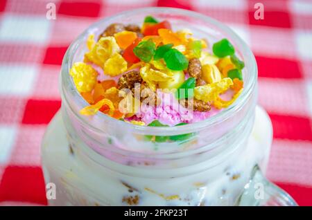 Colorati tutti frutti e frutta secca su gelato alla fragola mungere in un bicchiere Foto Stock