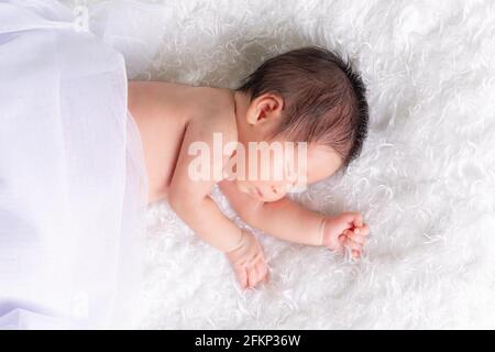 Ritratto di una bambina di un mese che dorme, neonato su una coperta bianca. Concept studio ritratto moda neonato. Foto Stock