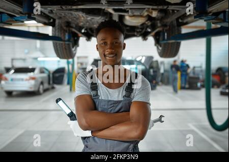 Il lavoratore maschile controlla le sospensioni dell'automobile, il servizio auto Foto Stock