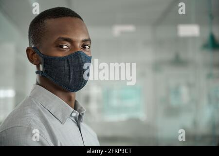 Uomo d'affari africano che indossa una maschera protettiva durante il lavoro Foto Stock