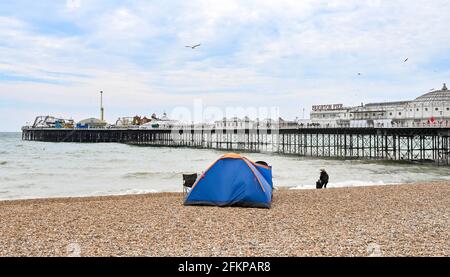 Brighton Regno Unito 3 maggio 2021 - una tenda di famiglia ambrata sulla spiaggia di Brighton come i visitatori godono la festa della Banca di maggio nonostante il tempo ventoso: Credit Simon Dack / Alamy Live News Foto Stock