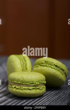 Macaron torte di colore verde chiaro. Si trovano su assi di pino bianco e nero. Foto Stock