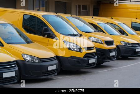 Furgoni di consegna gialli parcheggiati di fila Foto Stock