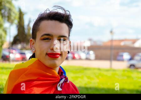Una ragazza transgender con la bandiera gay sulle spalle. Persone autentiche non binarie. Foto Stock