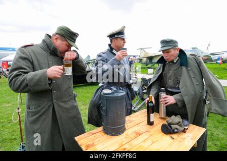 Reenactor vestiti in uniformi di ufficiali tedeschi della seconda guerra mondiale bevendo vodka su un prato. Festival VECCHIA AUTO Terra. 12 maggio 2019. Kiev Ucraina Foto Stock