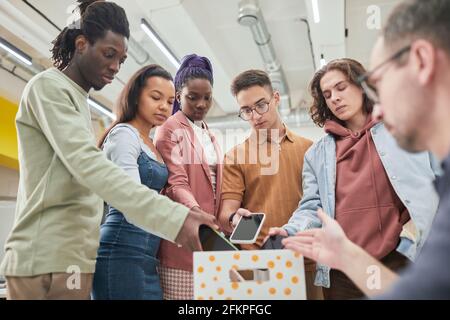 Gruppo eterogeneo di adolescenti che mette gli smartphone in scatola in classe no gadget a scuola, spazio di copia Foto Stock