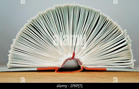 Primo piano di pagine piegate di un libro su superficie in legno Foto Stock