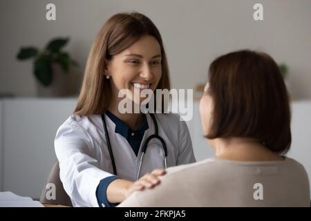 Una donna sorridente sostiene la paziente anziana alla riunione Foto Stock