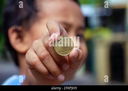 Mano del bambino asiatico che tiene una cinquanta moneta di Riyal di Halalas, soldi dell'Arabia Saudita, fuoco selezionato Foto Stock