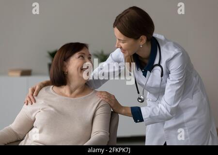 Donna sorridente, infermiera, comfort, paziente anziano in ospedale Foto Stock