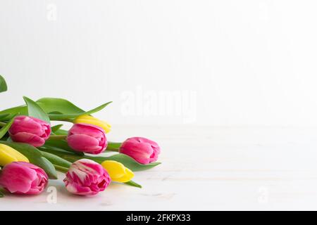 bouquet di tulipani rosa e giallo adagiato su legno bianco tabella con spazio di copia Foto Stock