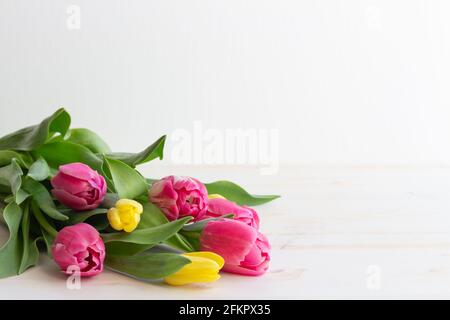 bouquet di tulipani rosa e giallo adagiato su legno bianco tabella con spazio di copia Foto Stock