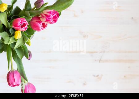 bouquet di tulipani rosa e giallo sparato dall'alto tavolo in legno bianco con spazio per la copia Foto Stock