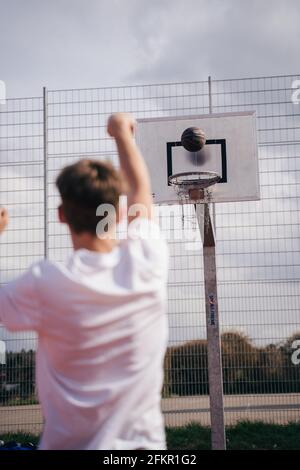 Il ragazzo lancia una palla da basket nel canestro