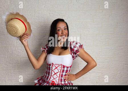 Partito brasiliano di giugno, celebrazione tipica in Brasile. Felice donna nera matura che svita il cappello di paglia e indossa il costume tradizionale junina. Divertimento, buon nome Foto Stock