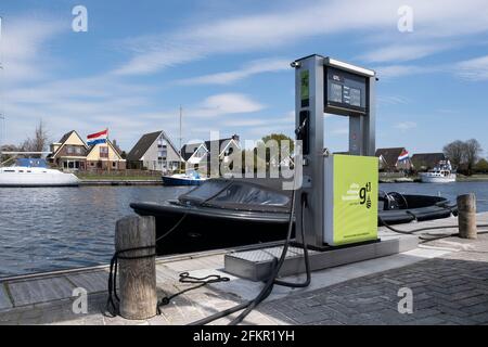 Stazione di benzina per il carburante pulito 98 benzina senza piombo lungo il lungomare con barche ormeggiate nel porto con la città di Lemmer, Paesi Bassi Foto Stock