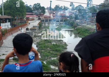 Kathmandu, Nepal. 03 maggio 2021. La gente guarda mentre i lavoratori nepalesi che indossano i dispositivi di protezione individuale (PPE) si accoppiano ai corpi†delle vittime di Covid-19 sulla riva del fiume Bagmati. Il governo nepalese ha vietato tutti i voli nazionali e internazionali fino al 14 maggio 2021, in quanto il numero di casi COVID-19 continua a salire nel paese. Credit: SOPA Images Limited/Alamy Live News Foto Stock