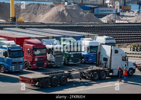 Terminal di carico TIS nel più grande porto di carico secco dell'Ucraina. Paesaggio industriale con fila di carrelli portacontainer e due operatori in caschi di sicurezza arancioni. O Foto Stock