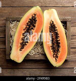 Frutta fresca di papaya tropicale in una scatola di consegna di legno sopra una vista dall'alto con fondo piatto in legno con spazio per la copia per alcuni messaggi pubblicitari Foto Stock