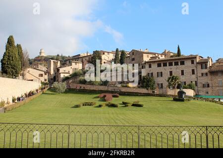 Prato verde rivolto lontano dalla Basilica di San Francesco d'Assisi in Italia. Città medievale Foto Stock