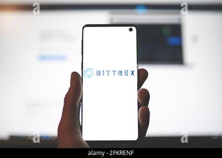 SWANSEA, UK - 1 MAGGIO 2021: Uomo che tiene uno smartphone con il logo dell'app Bittrex con sfondo sfocato del sito web. Scambio di criptovaluta, piattaforma di trading Foto Stock
