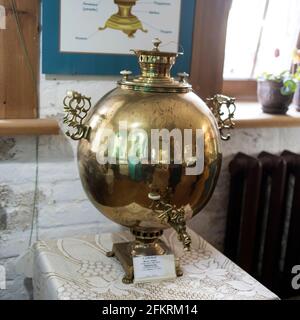 Un samovar rotondo di rame di una forma insolita del il xix secolo si erge su una sedia Foto Stock