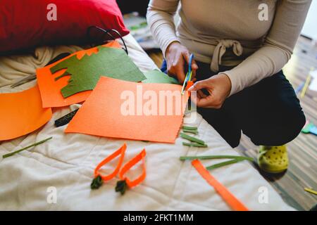 Mani di donna sconosciuta che tengono le forbici che tagliano il materiale a casa mentre facendo l'arte di decorazione casalinga e la copia di concetto di hobby artigianale spazio Foto Stock
