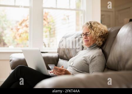 Senior donna shopping online su laptop Foto Stock
