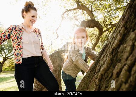 Ritratto di metà adulto madre guarda la figlia salire tree Foto Stock