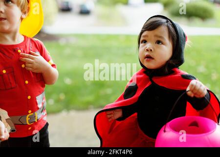 Ragazzo e una ragazza che indossa abiti fantasiosi costumi con dolcetto o scherzetto benna Foto Stock