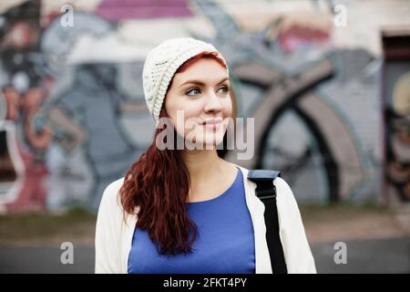 Giovane donna con lunghi capelli rossi, indossando il berretto lavorato a maglia Foto Stock