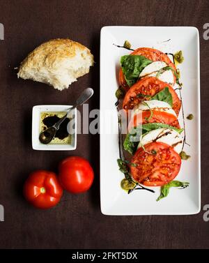 Fette di pomodori a grappolo e mozzarella con basilico e pane Foto Stock