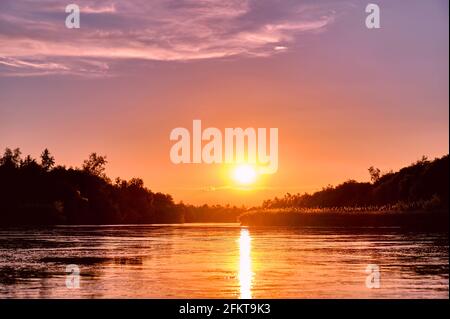 Atmosfera magica di una serata romantica; tramonto dorato sul fiume Foto Stock