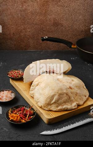 Tagliare la coda di grasso di agnello sul tavolo da cucina con sale e. pepe Foto Stock