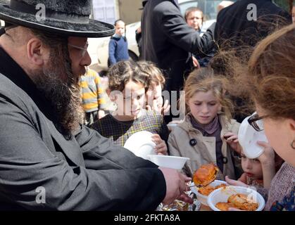 Bambini ebrei ortodossi in attesa di cibo e dolci serviti da un giusto ebreo durante i preparativi della Pasqua a Mea She'arim Gerusalemme. Foto Stock