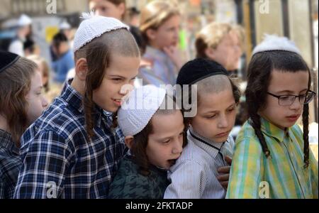 Bambini ebrei ortodossi in attesa di cibo e dolci serviti da un giusto ebreo durante i preparativi della Pasqua a Mea She'arim Gerusalemme. Foto Stock