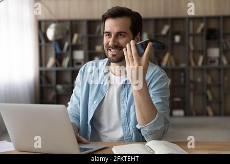 Uomo d'affari sorridente che registra un messaggio vocale audio sullo smartphone e parla Foto Stock