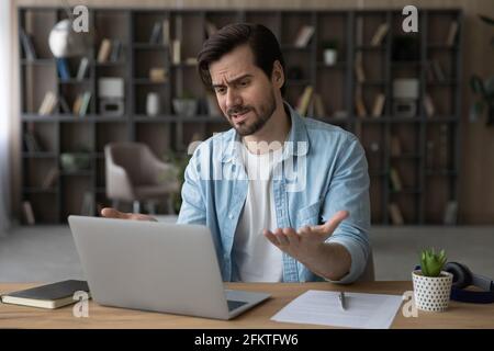 Uomo d'affari insoddisfatto insoddisfatto che guarda lo schermo del laptop, leggendo le cattive notizie Foto Stock