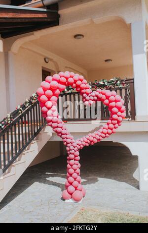 Immagine verticale di un grande rosso a forma di cuore palloncini ornamento in un cortile di casa Foto Stock