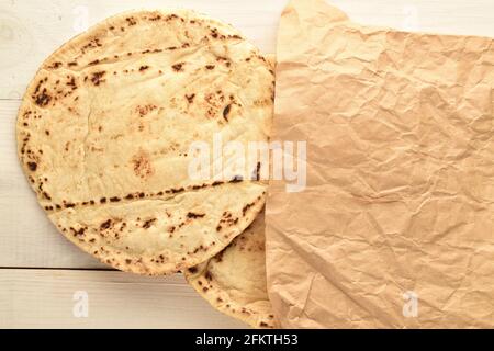 Diversi pita appena sfornati in una borsa di carta, primo piano, su un tavolo di legno. Foto Stock