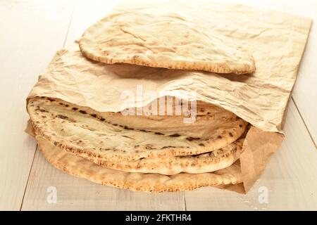 Diversi pita appena sfornati in una borsa di carta, primo piano, su un tavolo di legno. Foto Stock