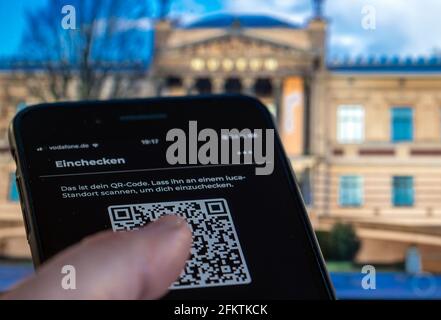 14 aprile 2021, Meclemburgo-Pomerania occidentale, Schwerin: Nuova applicazione di avvertimento Corona su uno smartphone iPhone di fronte al Museo di Stato. L'app Luca consente la trasmissione crittografata dei dati dei contatti per gli host e i loro ospiti, nonché il monitoraggio sicuro dei dati. Foto: Jens Büttner/dpa-Zentralbild/ZB Foto Stock