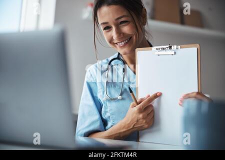 Bella dottoressa che dà consultazione online in clinica Foto Stock