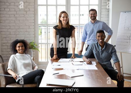 Ritratto di felici colleghi di corsa mista che posano in un ufficio moderno. Foto Stock