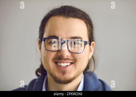 Studio ritratto di felice intelligente giovane uomo in occhiali con sorriso aperto e cordiale Foto Stock