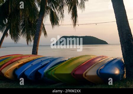 Le barche da rafting si trovano lungo la spiaggia. Barche multicolore sulla spiaggia che si affaccia su una piccola isola. Foto Stock