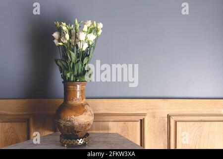 Camera in stile retrò. Vase vecchio di argilla con rose di fiori bianchi sullo sfondo di una parete vuota grigia. Interno d'epoca di una vecchia casa soggiorno. Decorazioni e interni in vecchio stile. Foto di alta qualità
