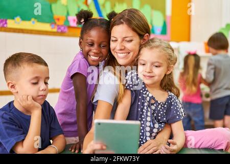 I bambini e i bambini prendono un selfie con il computer tablet in asilo o centro di assistenza post-scuola Foto Stock